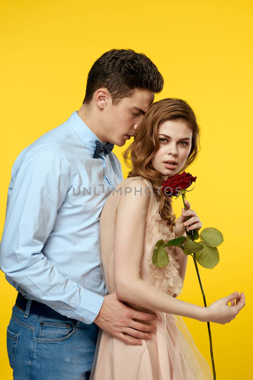 Enamored man and woman with red rose on yellow background cropped view close-up romance by SHOTPRIME