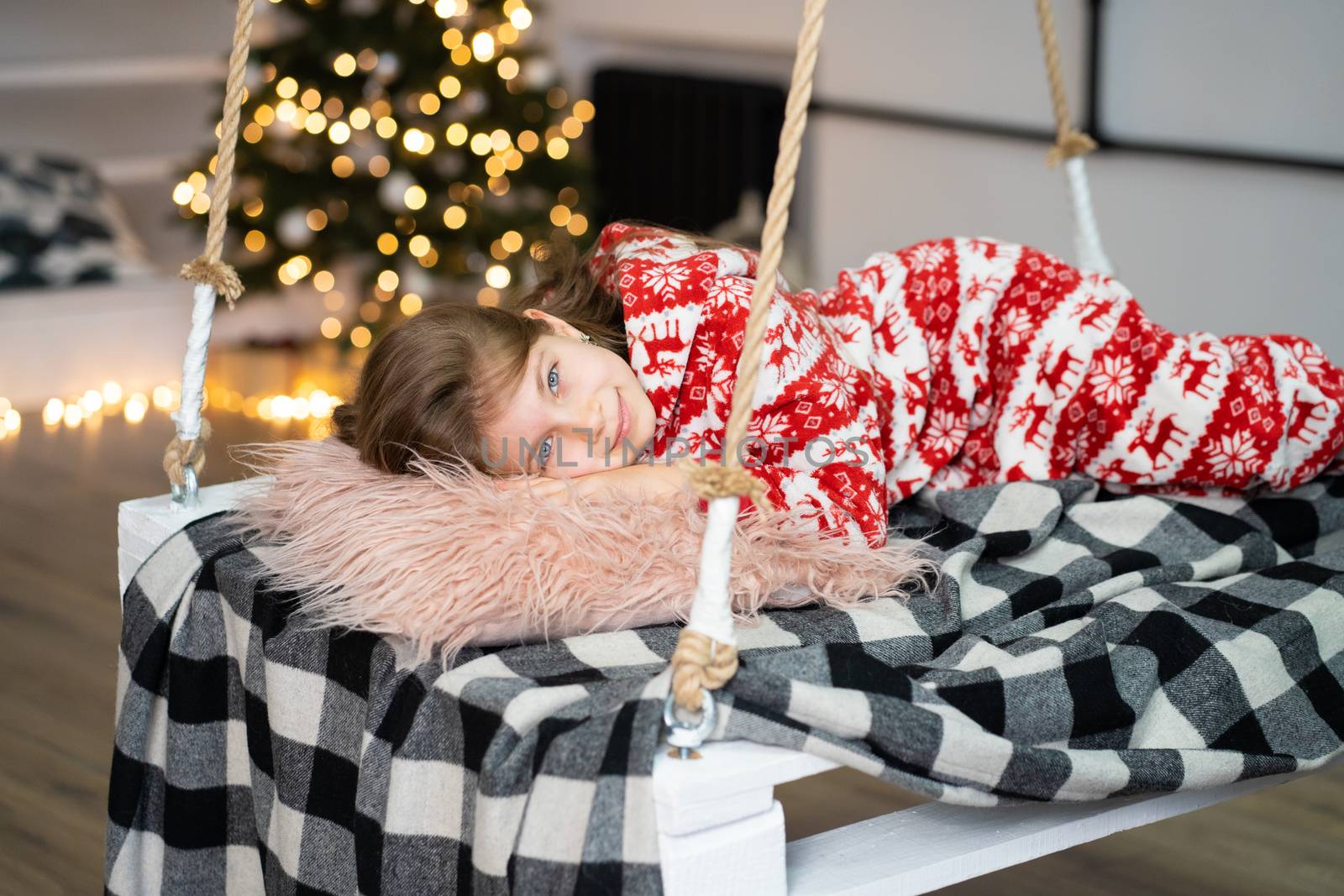 A little girl in pajamas can't sleep on a festive night. Christmas magic fairy tale. Happy childhood.