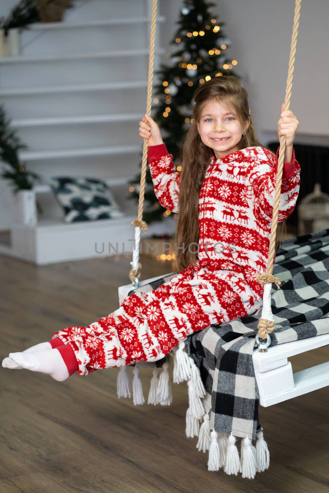 A little girl in pajamas can't sleep on a festive night. Christmas magic fairy tale. Happy childhood.