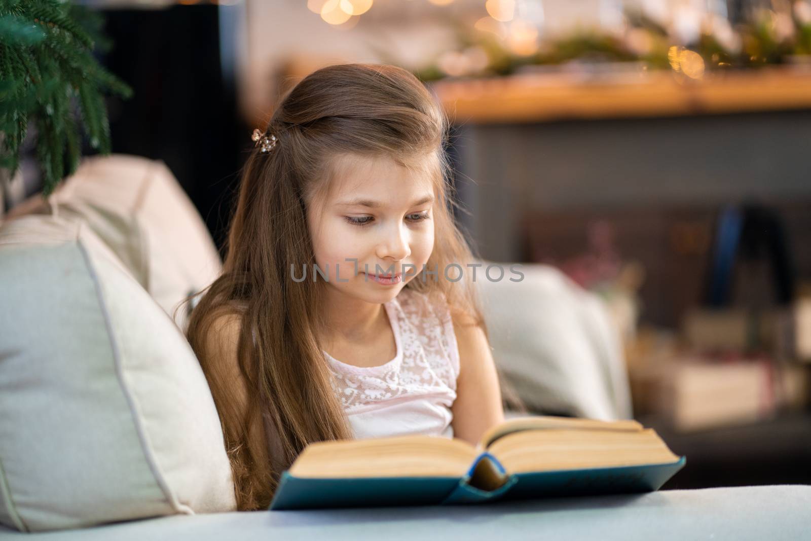 A little girl is reading an interesting book. Education and leisure of children.