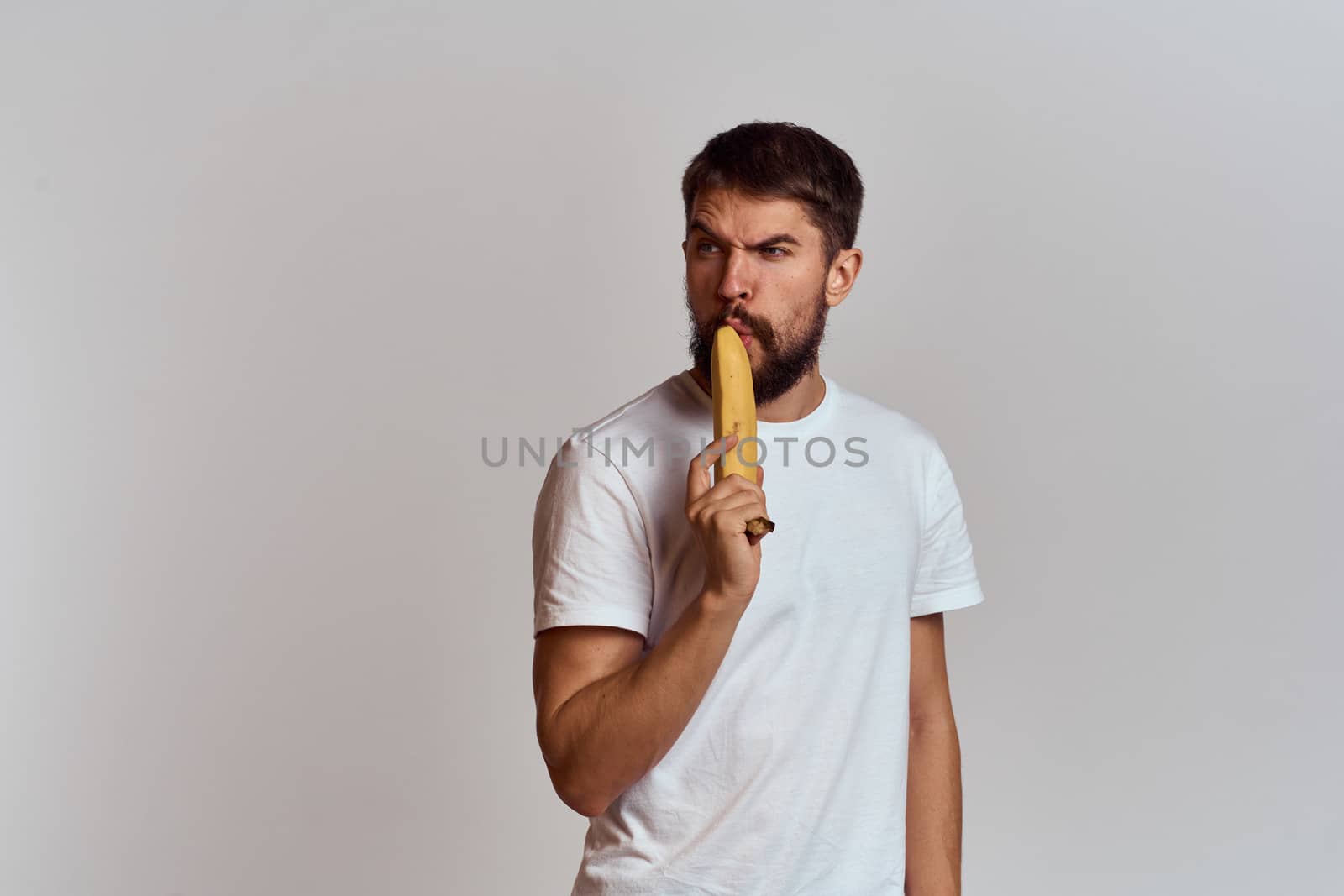 Cheerful man with a banana in his hands on a light background fun emotions Cropped view Copy Space by SHOTPRIME