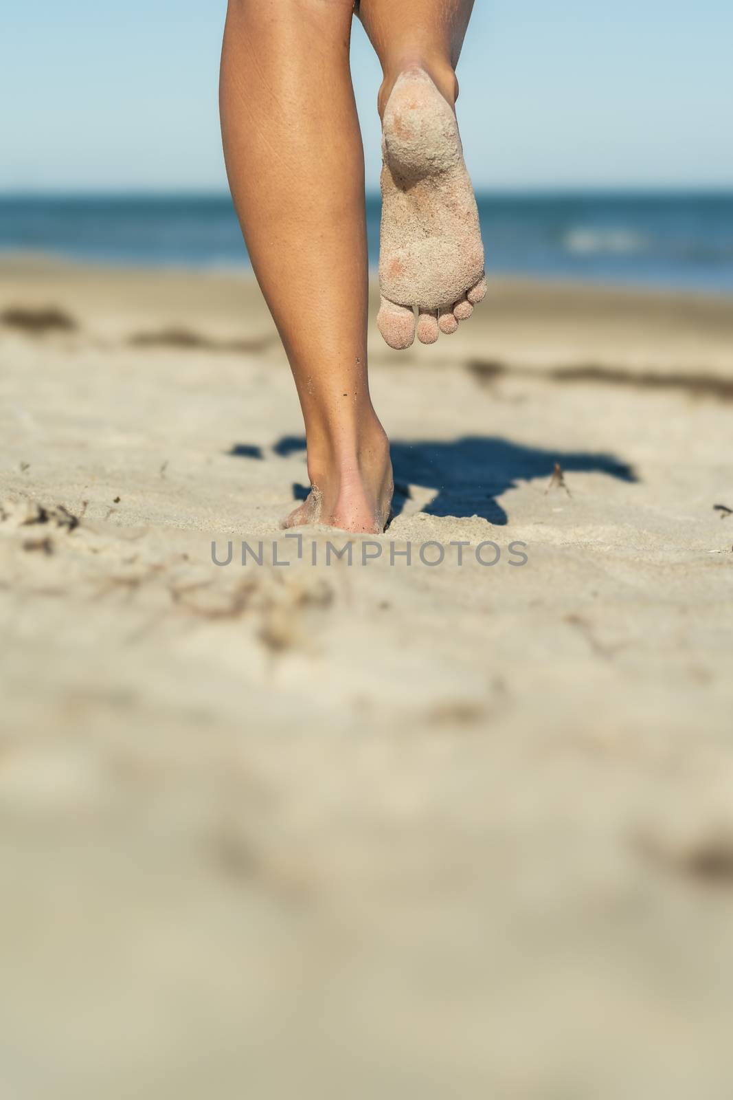 A gorgeous model walks in the sand at the beach on a beautiful day