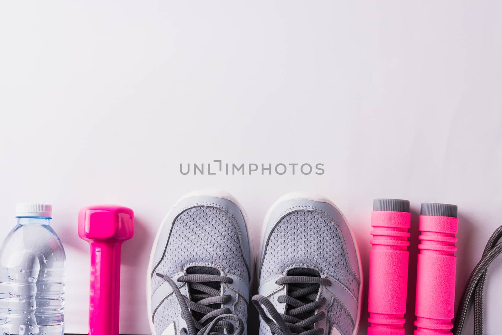 Pair sports shoes, headphones, dumbbell and water bottle on whit by Sorapop