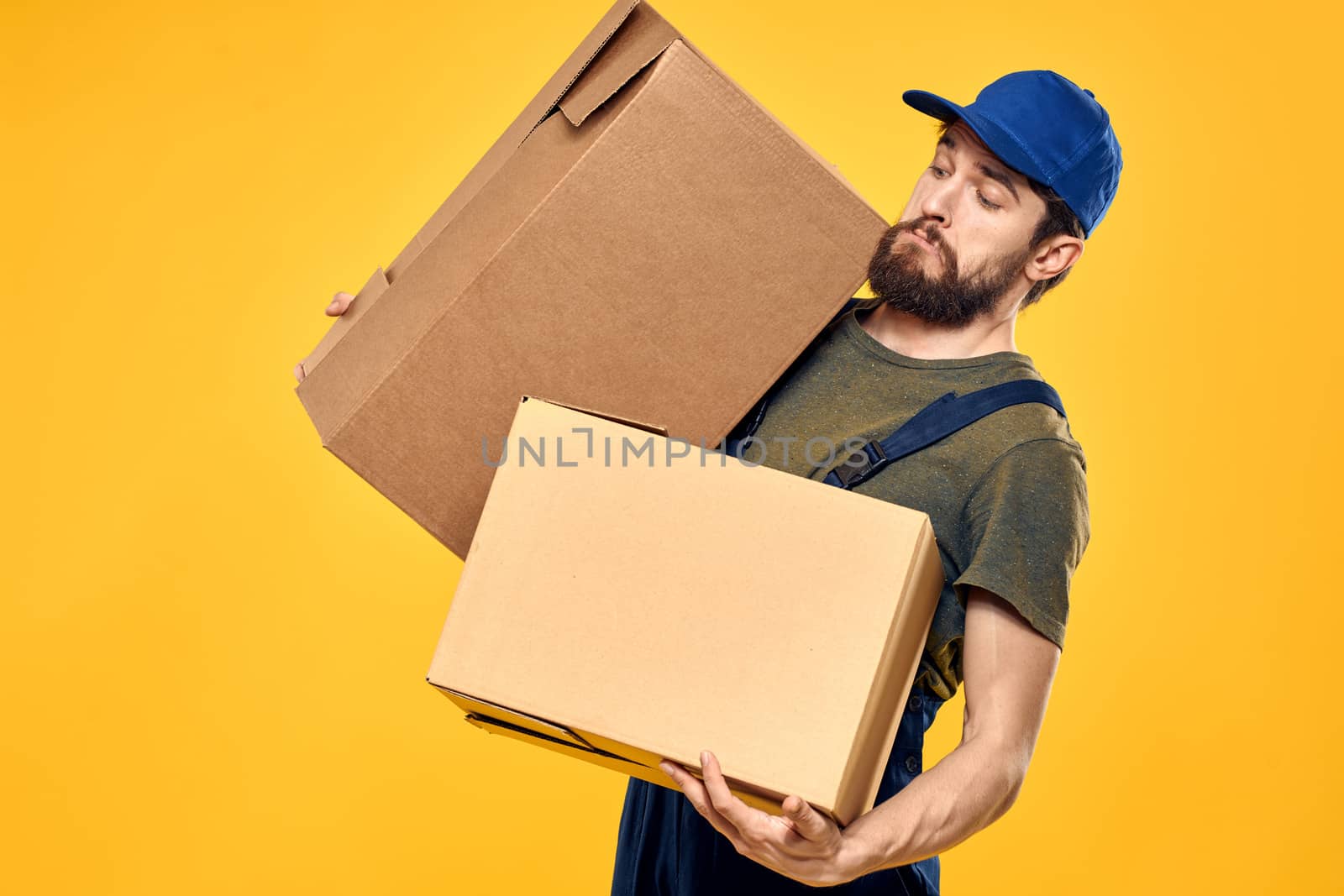 A man in a working form a box with loading tools yellow background. High quality photo