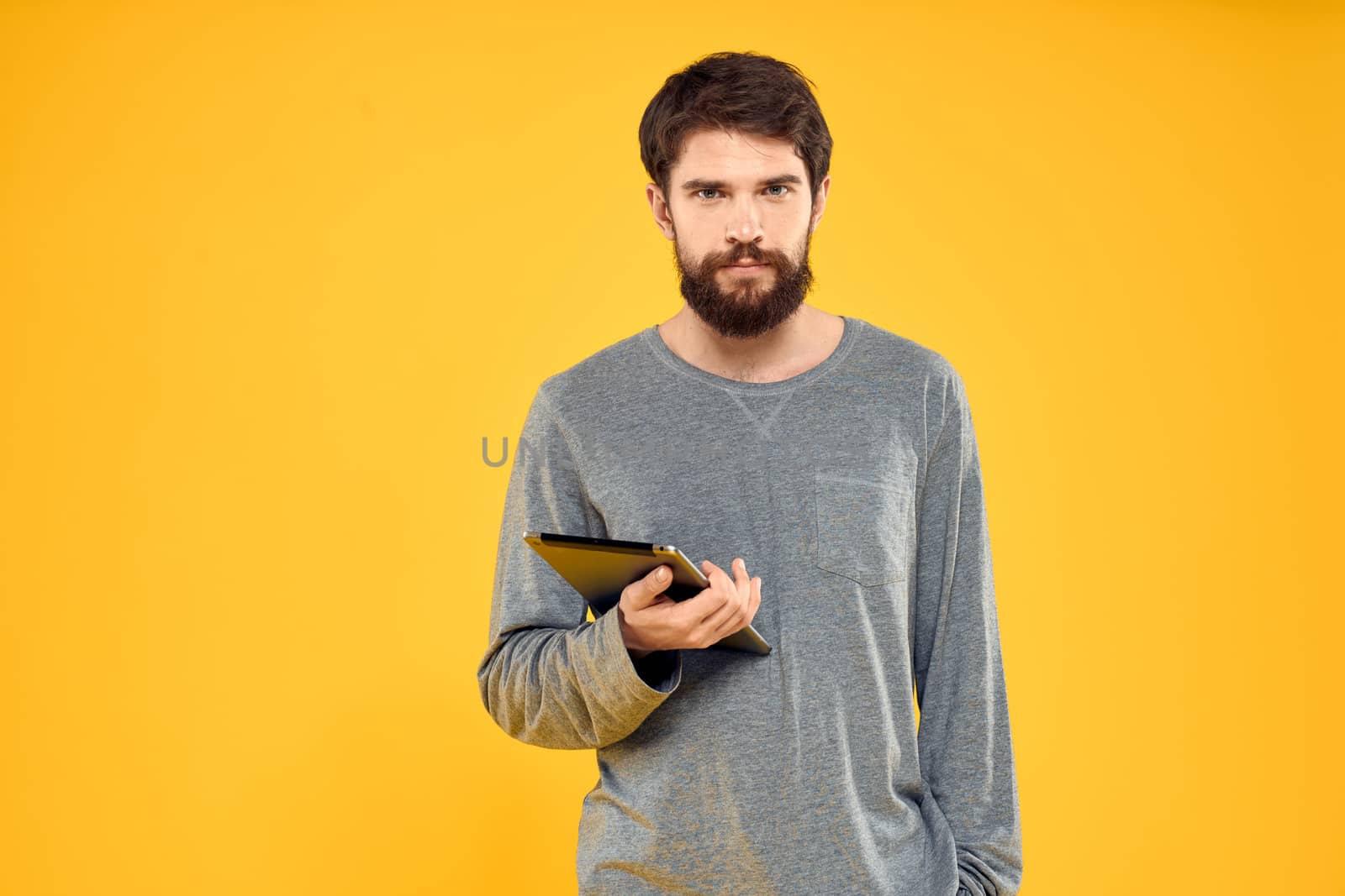 Emotional man with tablet in hands technology internet device lifestyle yellow background. High quality photo