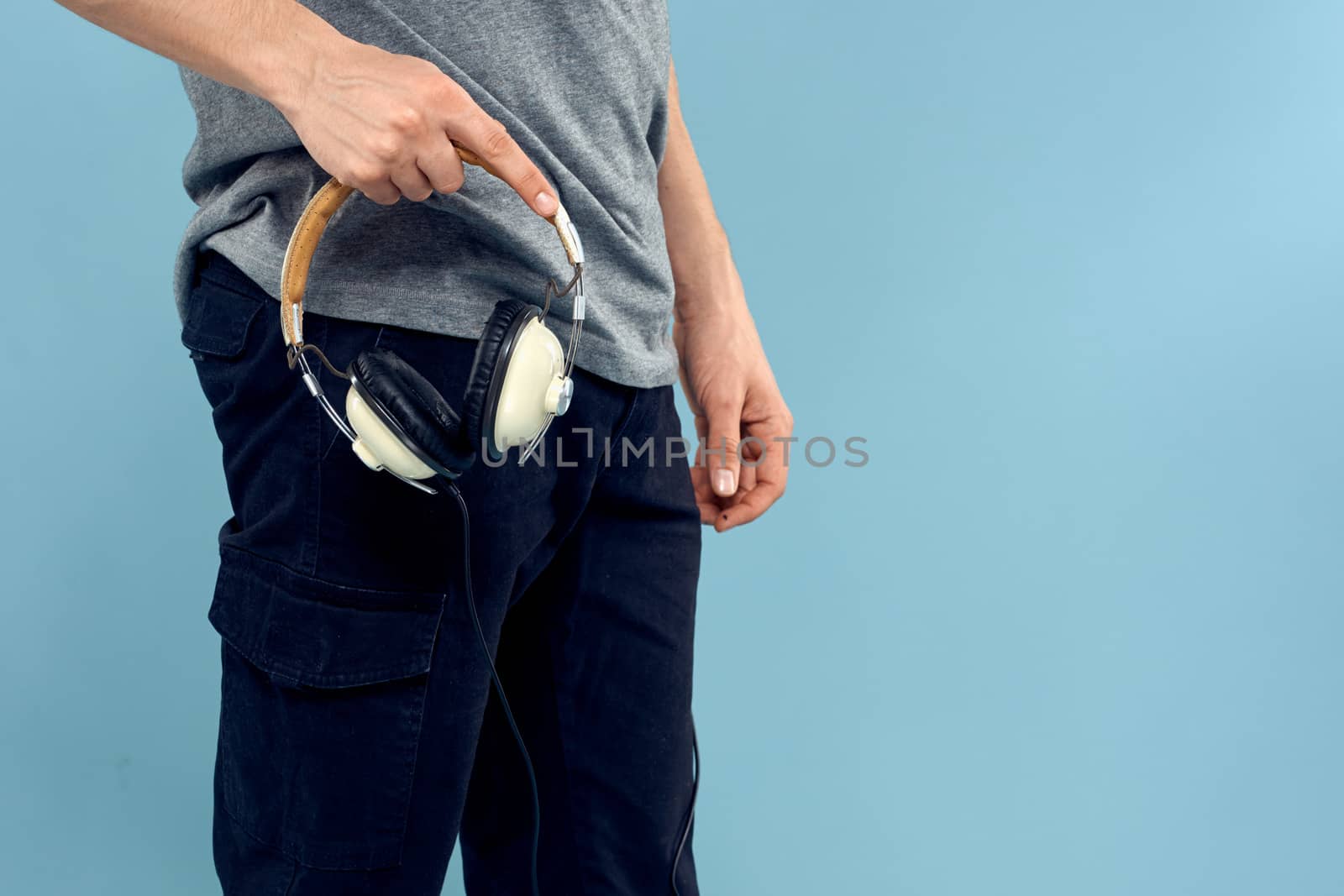 Headphones in man hands cropped view music technology blue background. High quality photo