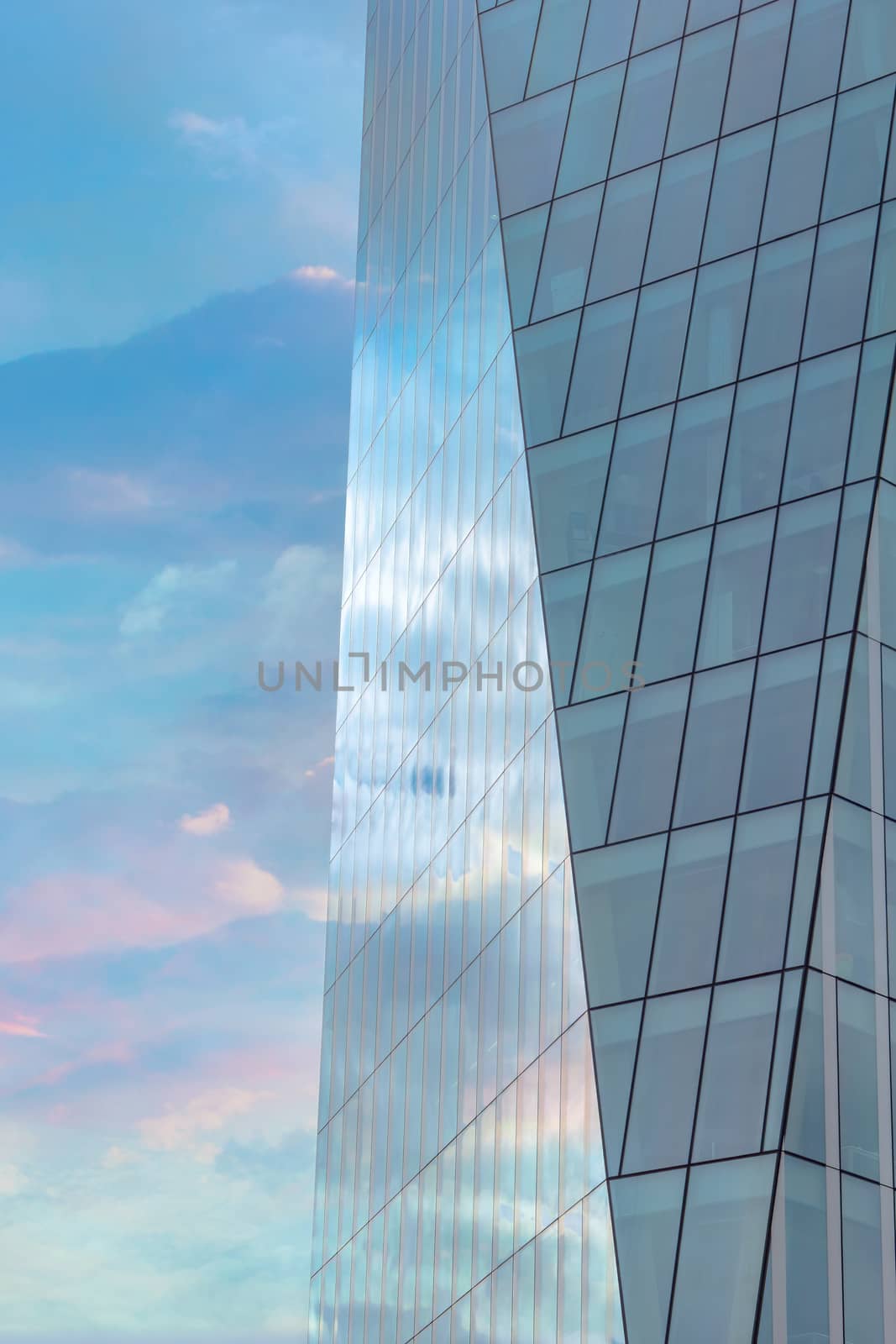 Colorful cloudy sky reflected in the exterior glass facade of a modern corporate building