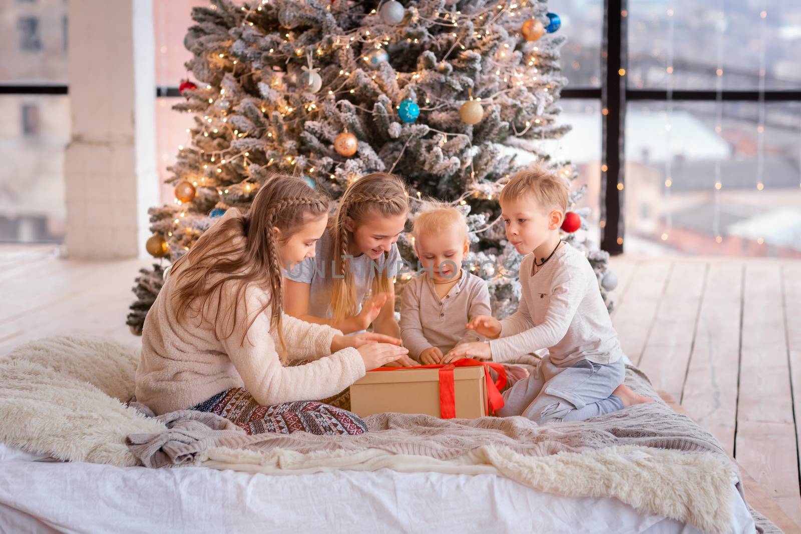 Happy kids having fun and opening presents near christmas tree.