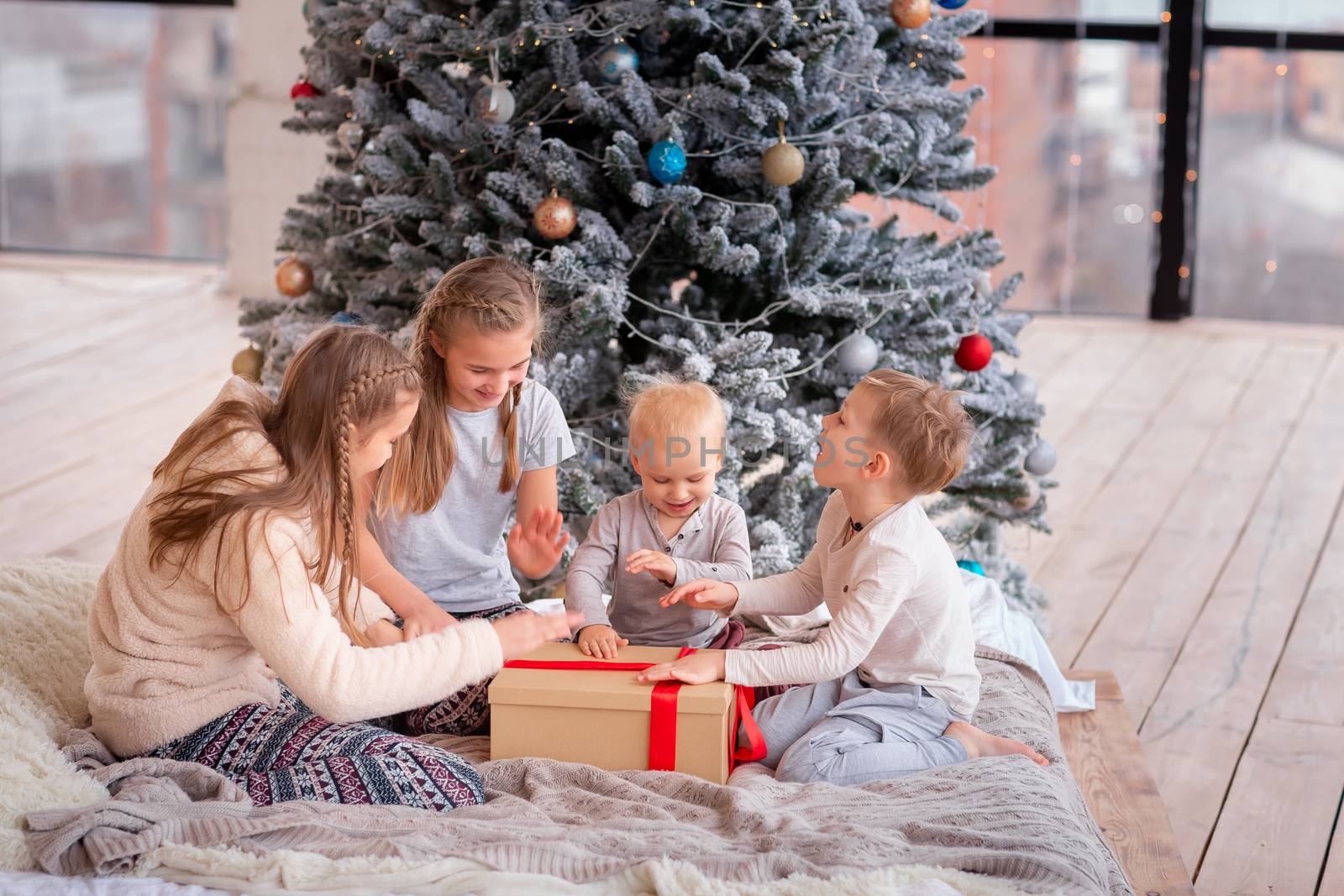 Happy kids having fun and opening presents near christmas tree.