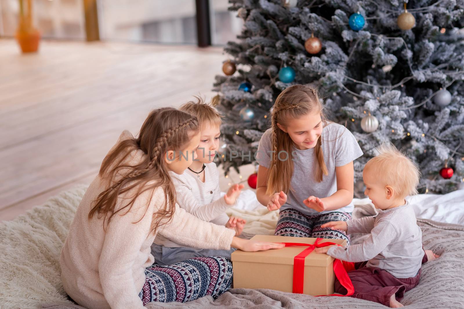 Happy kids having fun and opening presents near christmas tree.