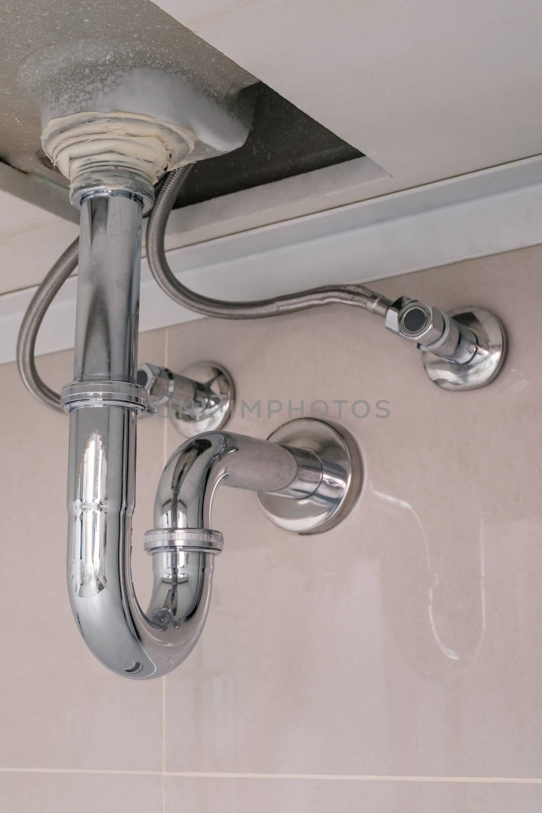 under sink plumbing and drainage with siphon system in modern bathroom, shallow depth of field