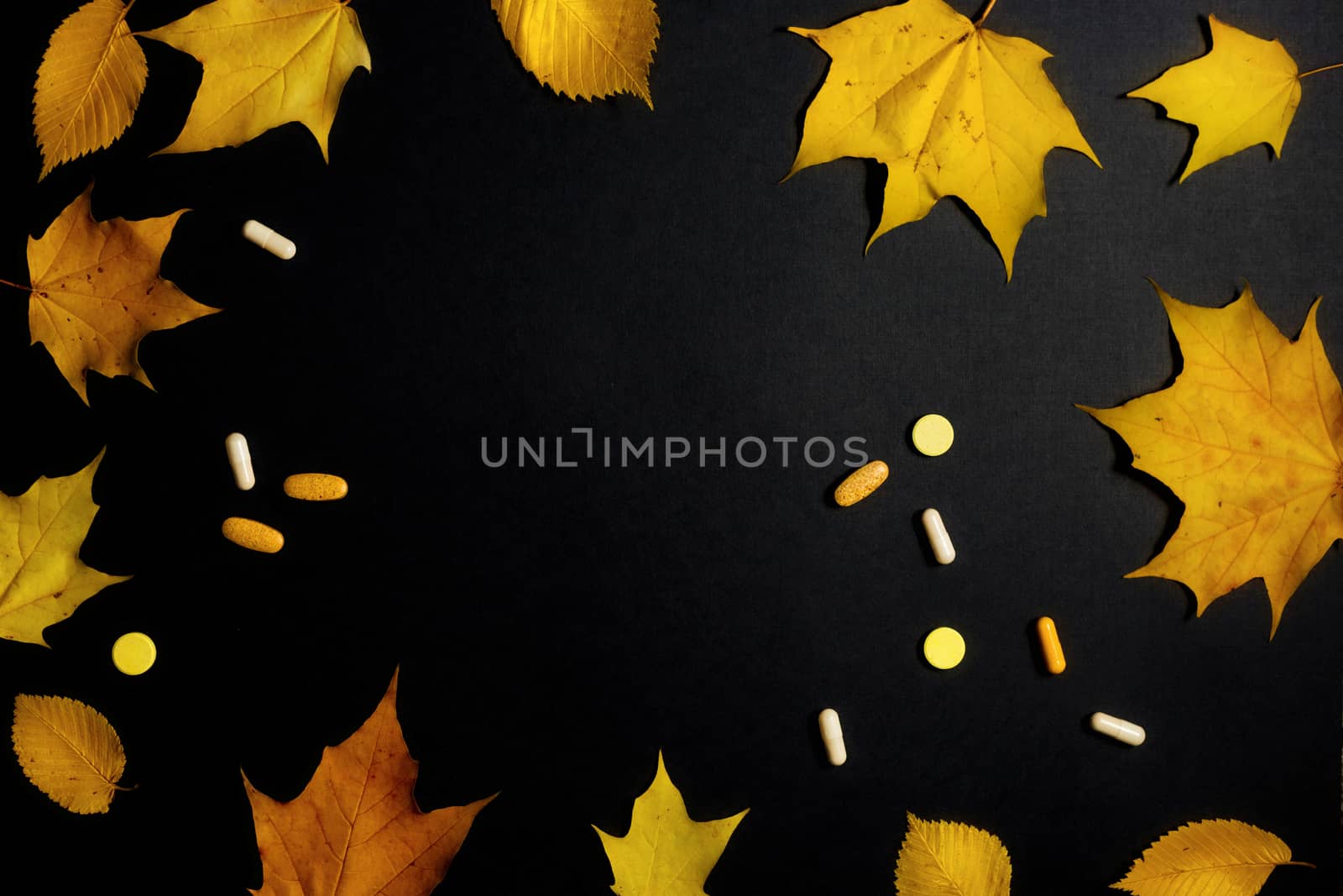 Autumn fallen leaves and medicines on black background