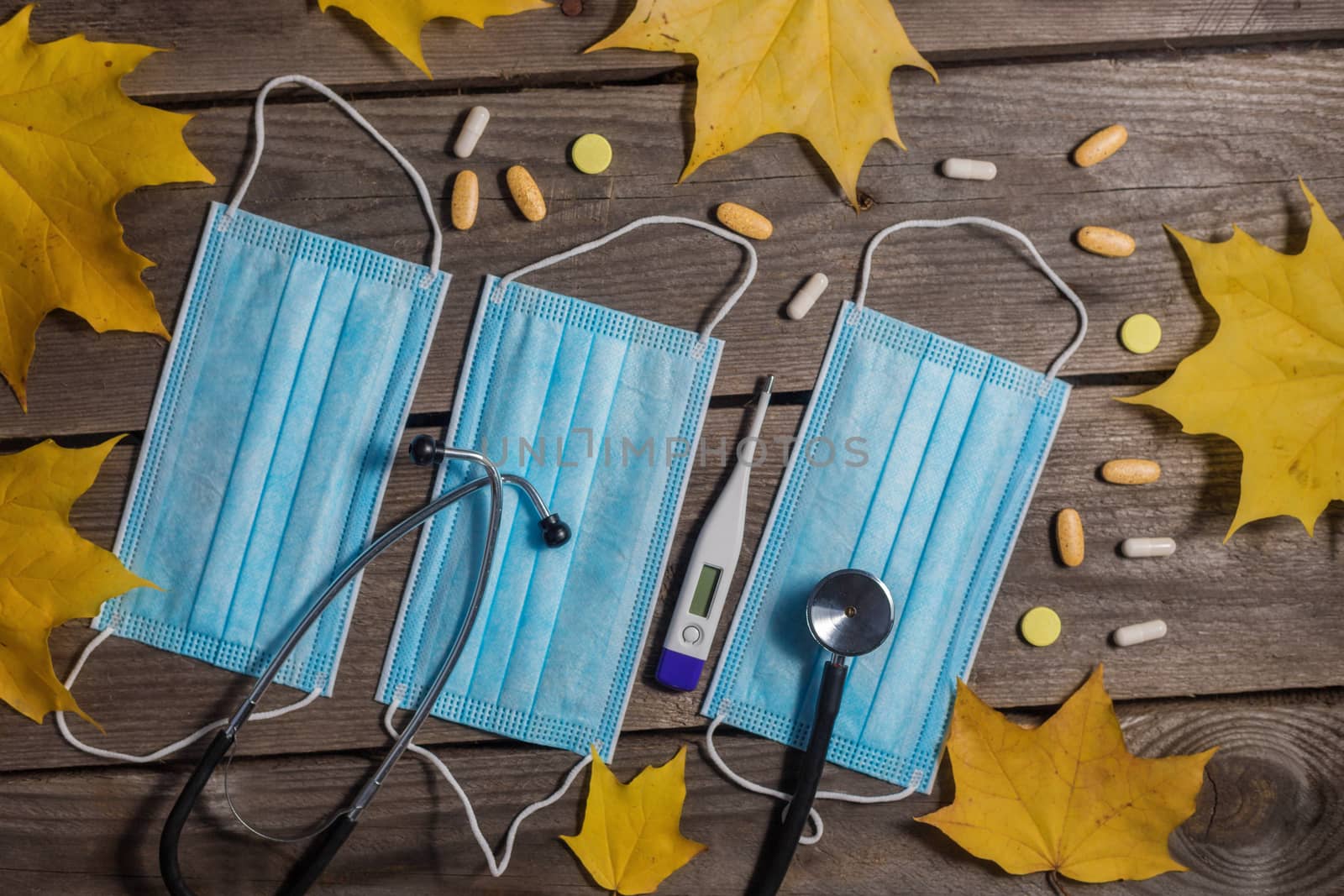 .Medical masks, stethoscope and thermometer on wooden background.