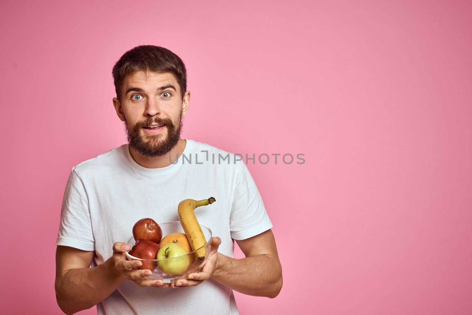 energetic man with fresh fruit in a cup on a pink background copy space. High quality photo