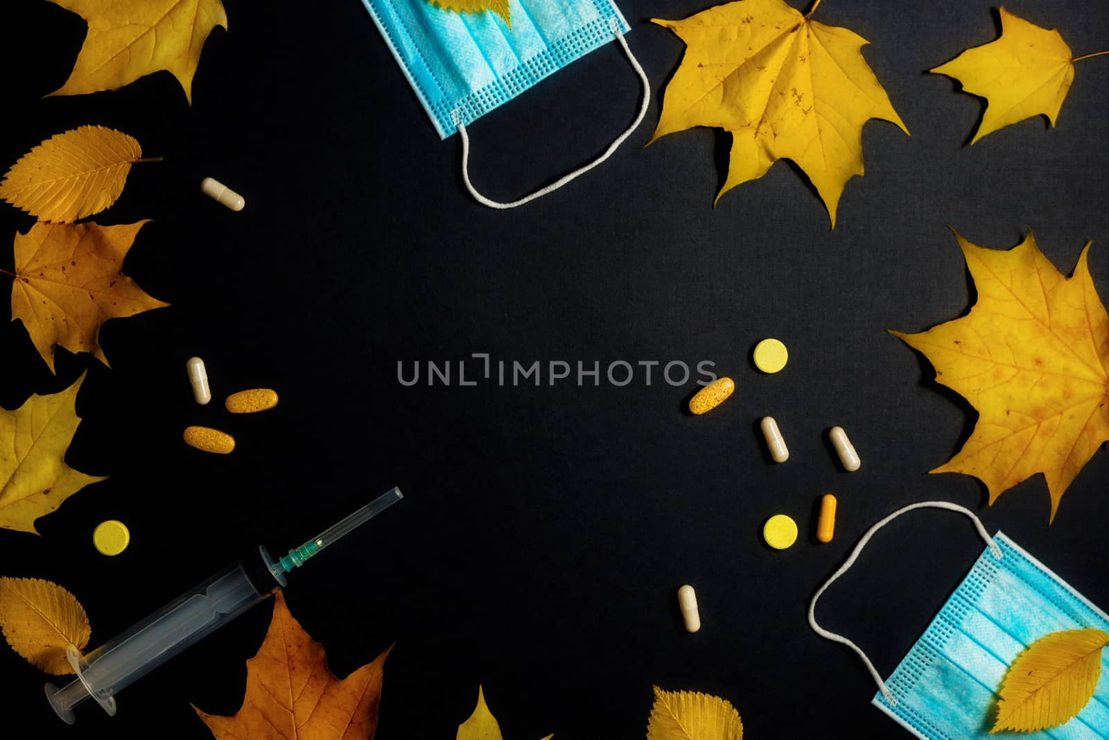 Autumn fallen leaves and medical masks and medicines on black background