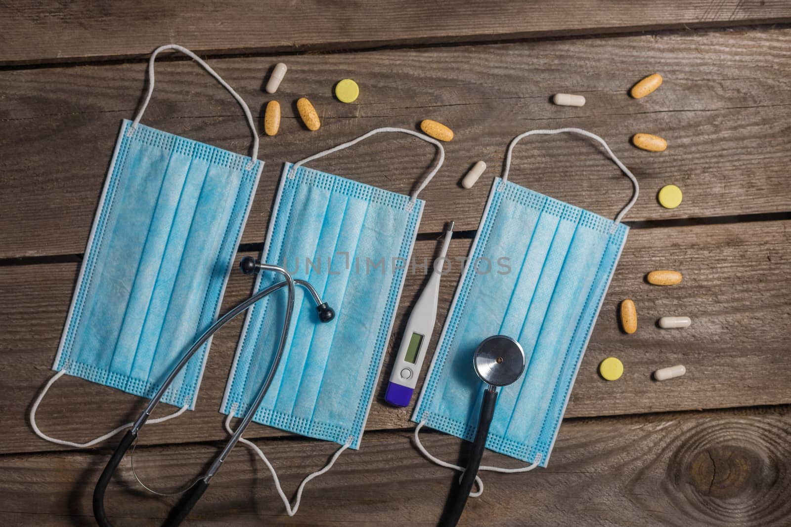 .Medical masks, stethoscope and thermometer on wooden background.