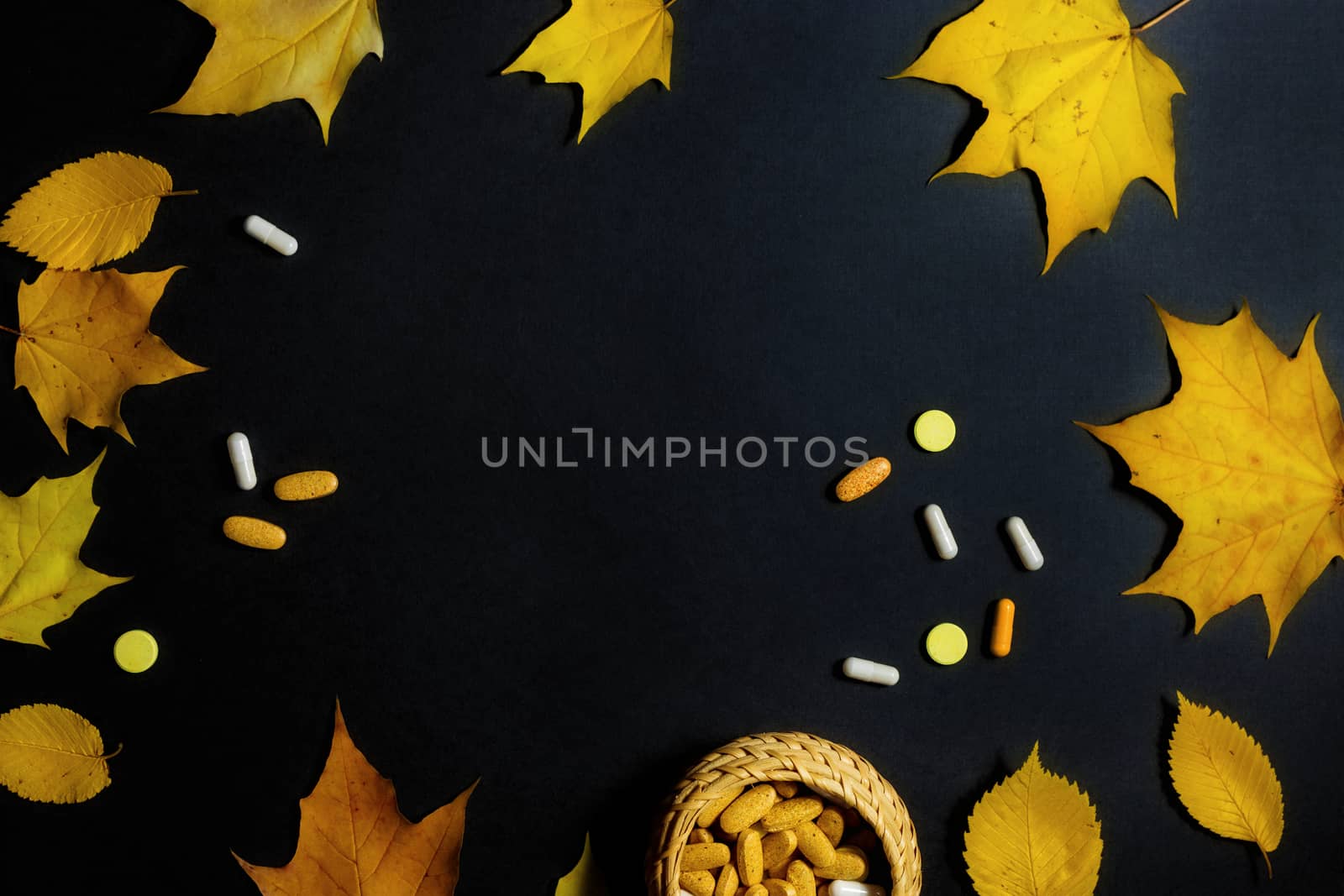 Autumn fallen leaves and medicines on black background.