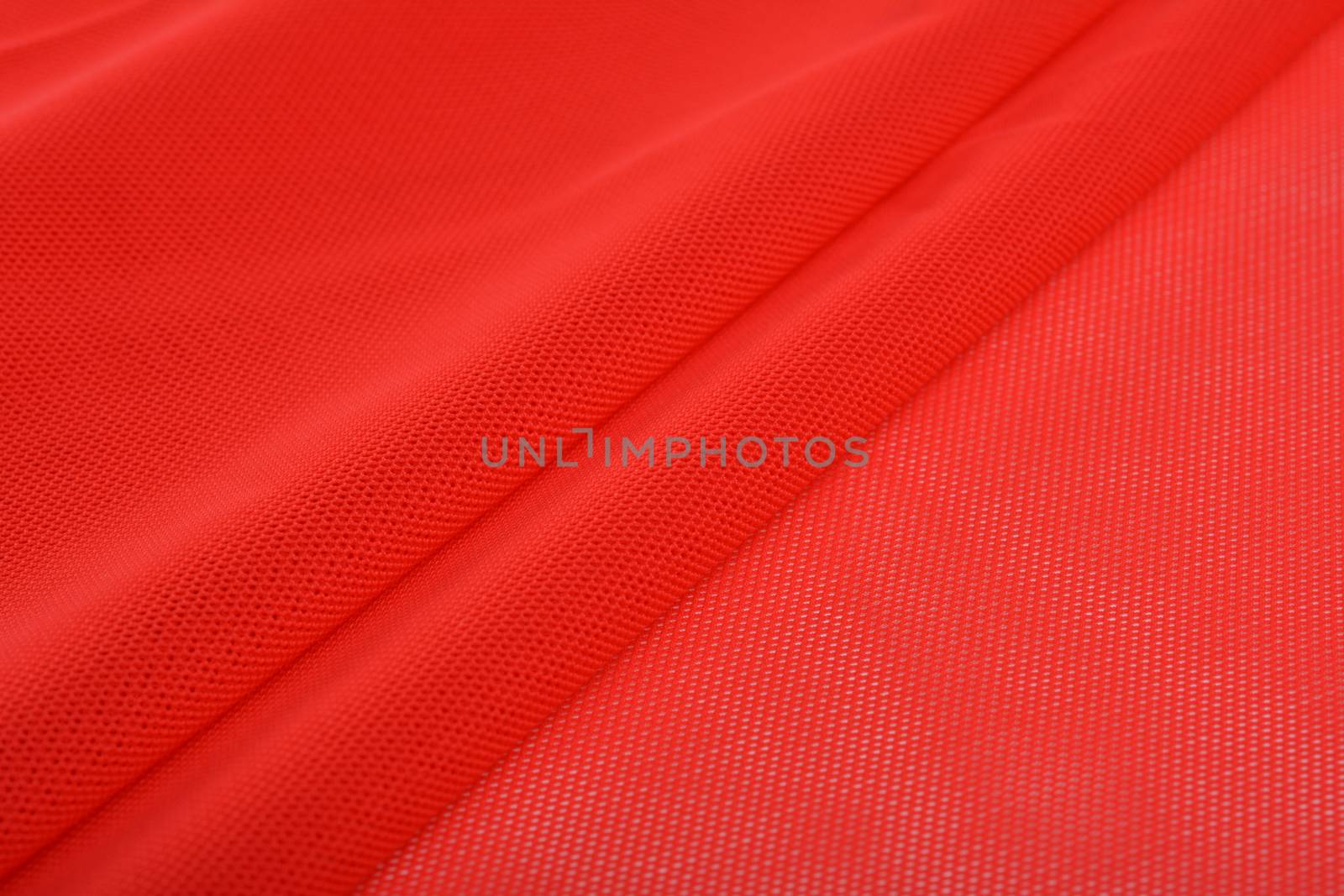 red Knitted elastic fabric, weaving of threads texture, crumpled fold. For underwear, sports clothes and swimwear. Space for text.