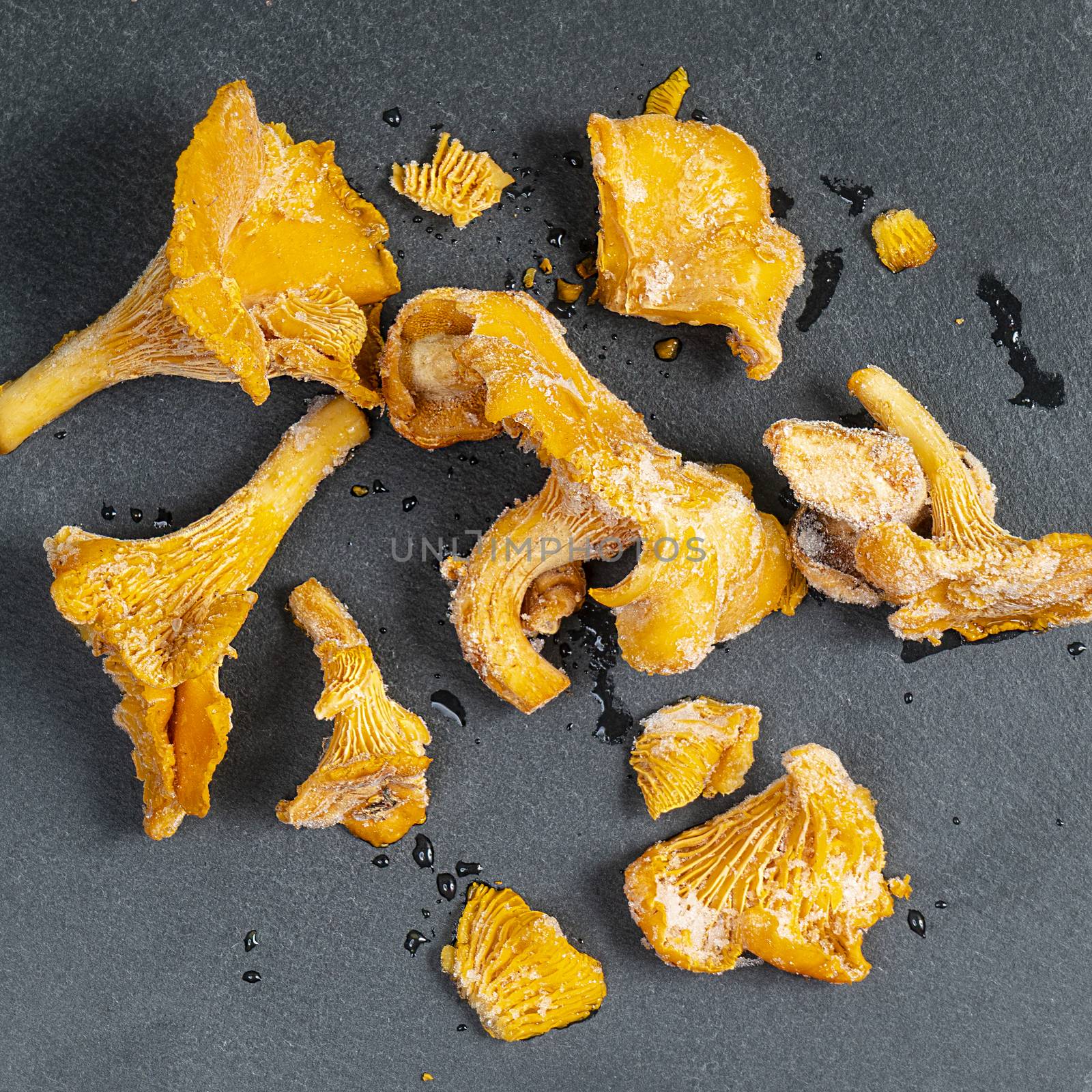 Some frozen chanterelle,  Cantharellus cibarius,  mushrooms on a black surface