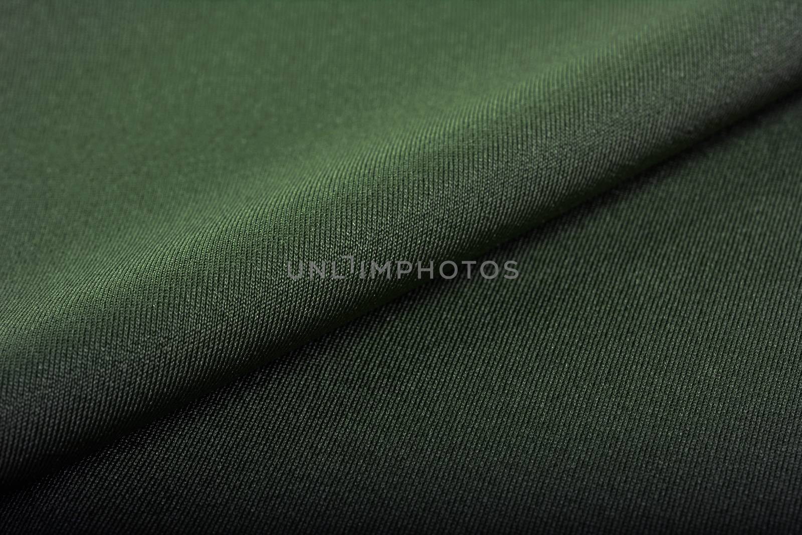 green Knitted elastic fabric, weaving of threads texture, crumpled fold. For underwear, sports clothes and swimwear. Space for text.