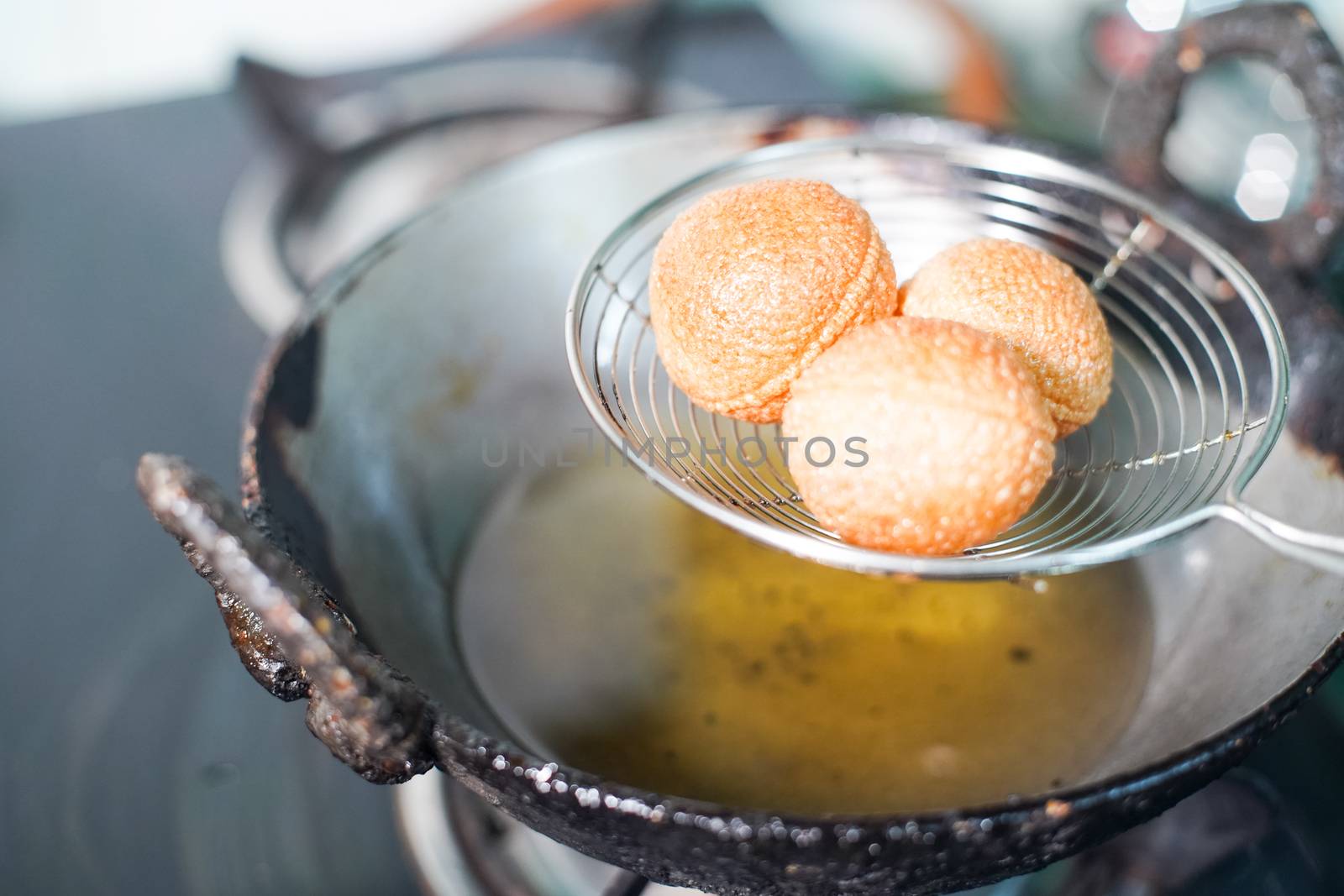 shot of north indian street food snack gol gappe pani puri or puchke being fried from dough in hot oil to make them round hollow golden ball spheres by Shalinimathur