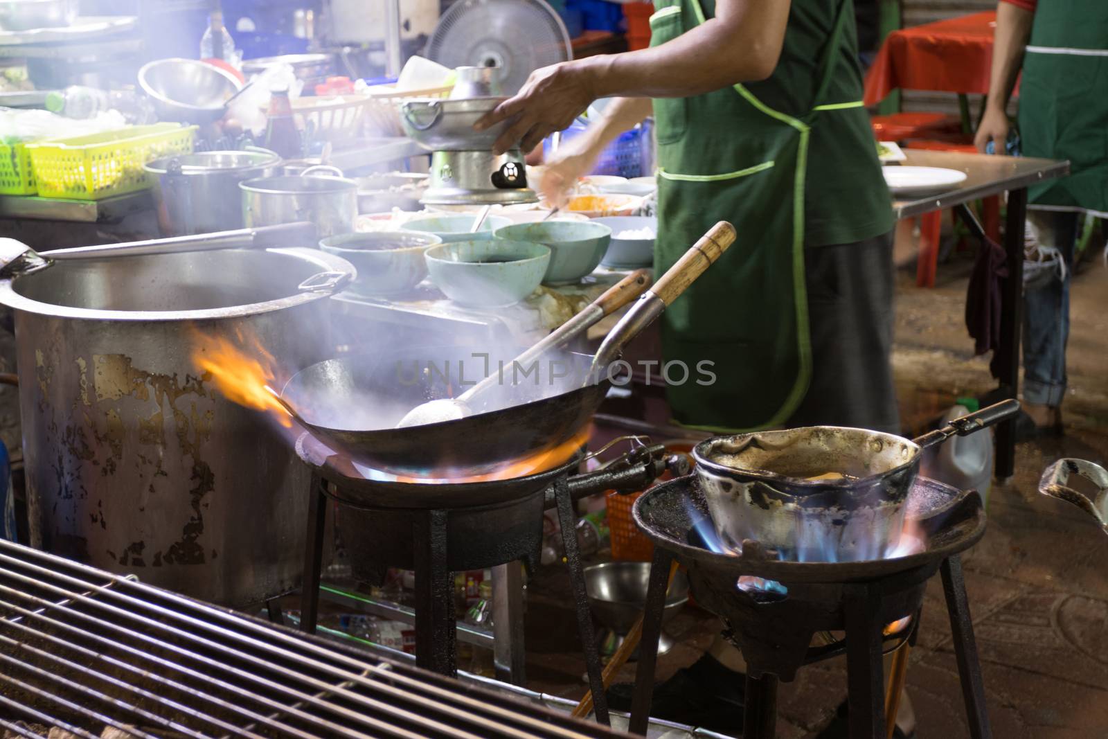 Chef is stirring cooking in wok at street food 