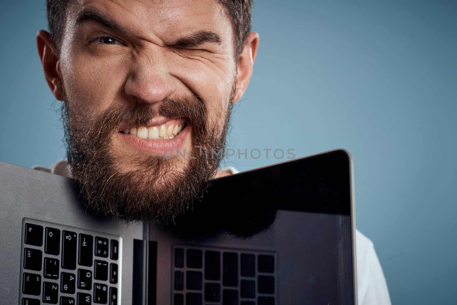 portrait of emotional man with open laptop on blue background cropped view. High quality photo