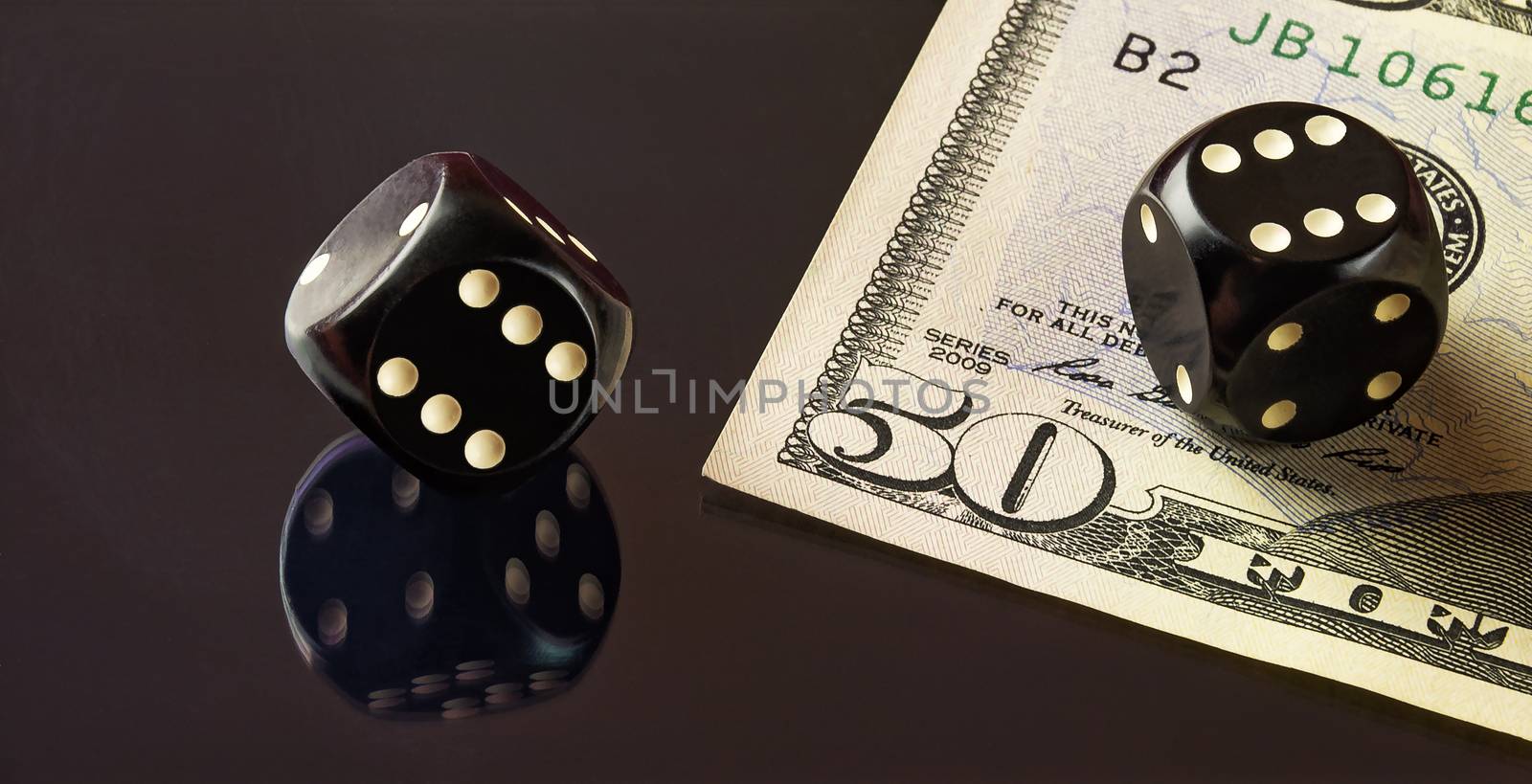 On the mirror surface reflects the black dice to play poker and is a banknote fifty dollars.