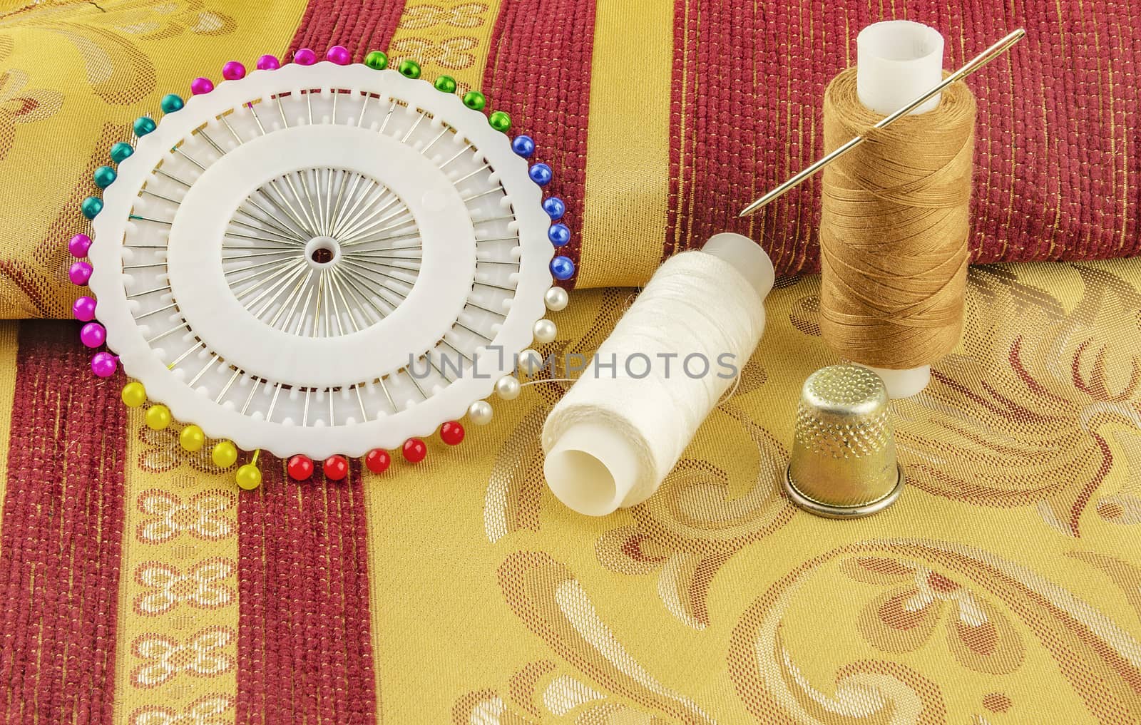 At curtain fabrics are two reels of thread for sewing with needle and thimble