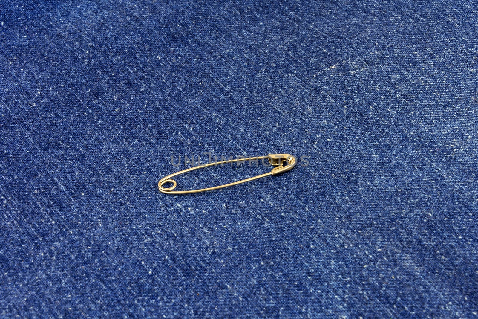 Metal buttoned pin lies on blue jeans material