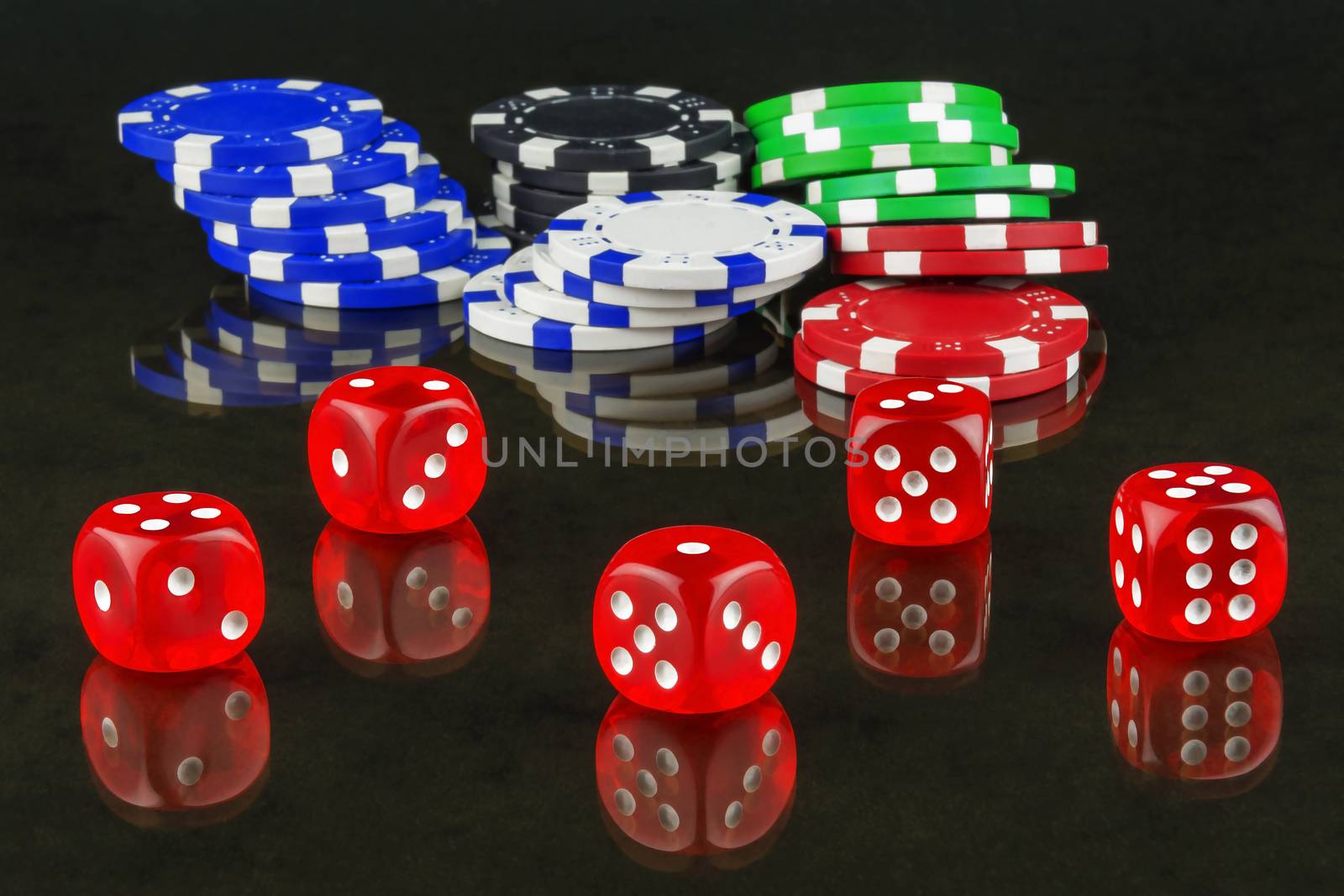 On mirror surface are casino chips and dices for playing poker by Grommik