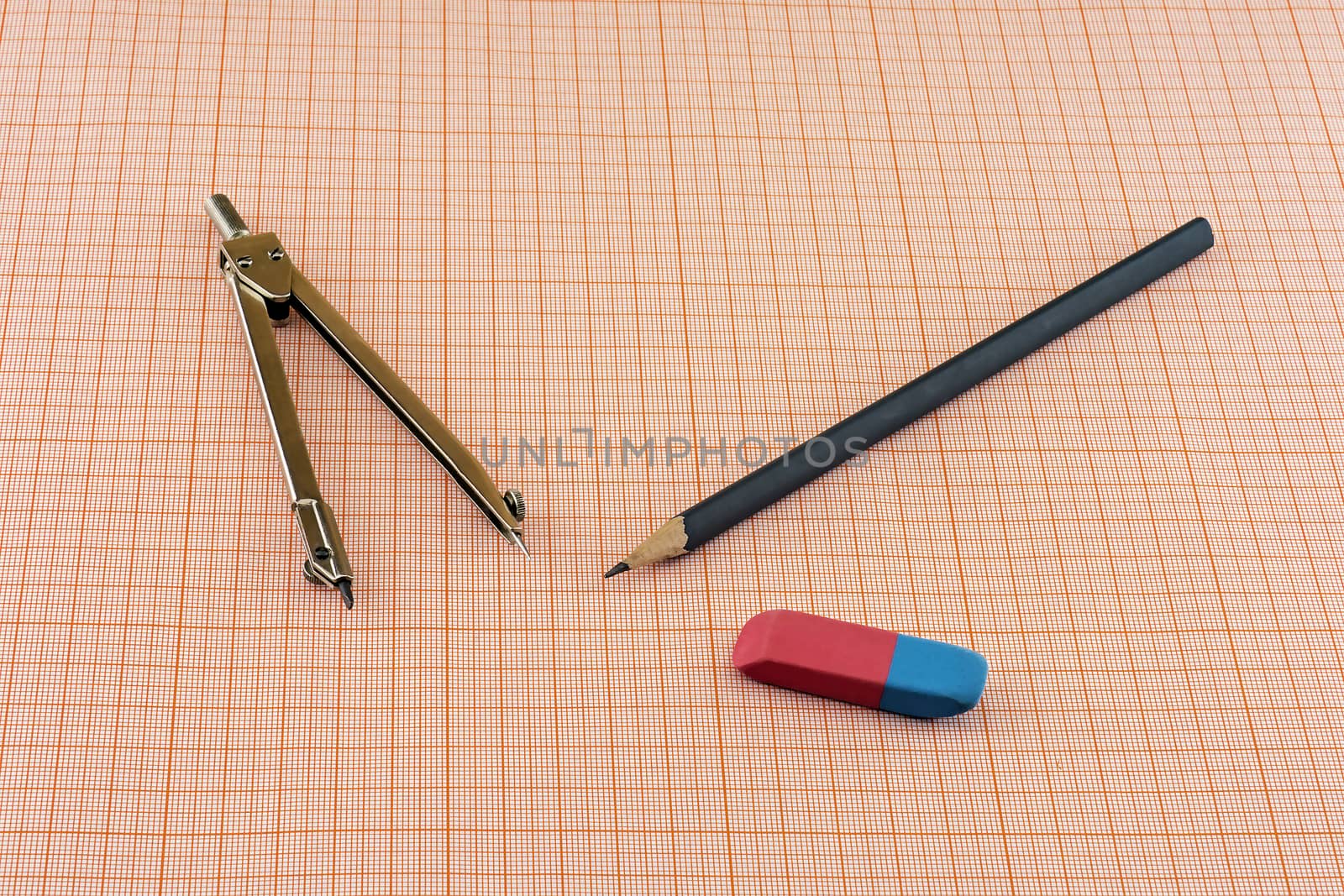 Compasses, pencil and eraser lying on a sheet of graph paper by Grommik