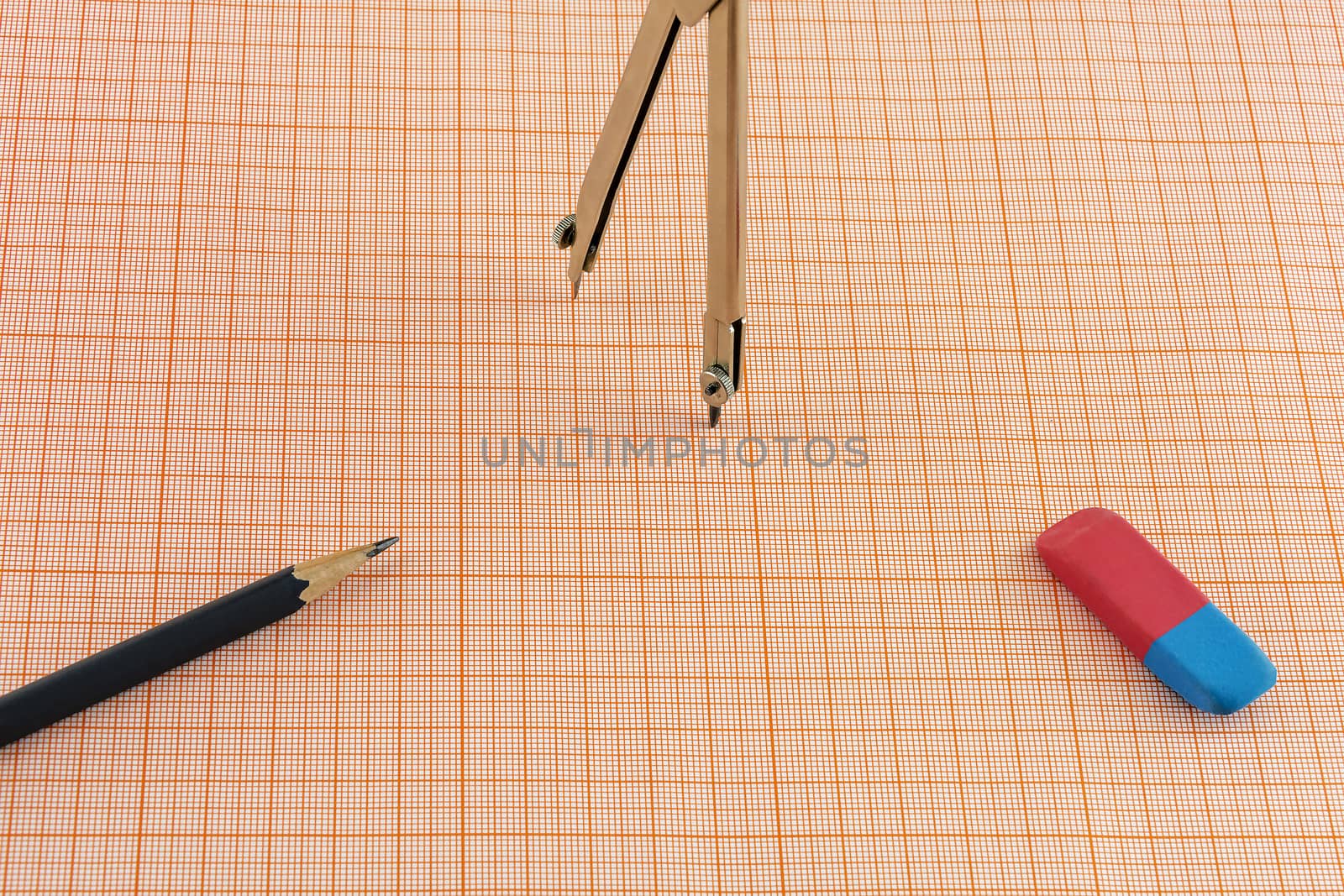 On a sheet of graph paper are the compasses and a pencil with an eraser