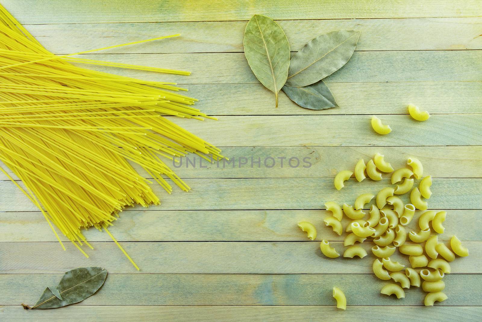 Pasta and bay leaf on wooden surface by Grommik