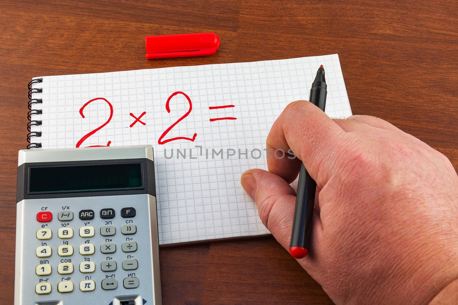 Man's hand writing equation on the notebook sheet in a cage by Grommik