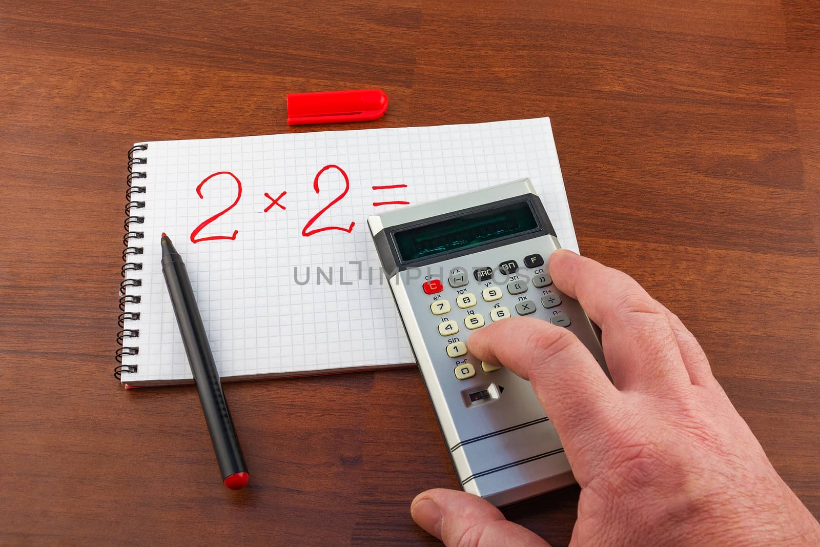 Man's hand pushes the button on the calculator solving the equation