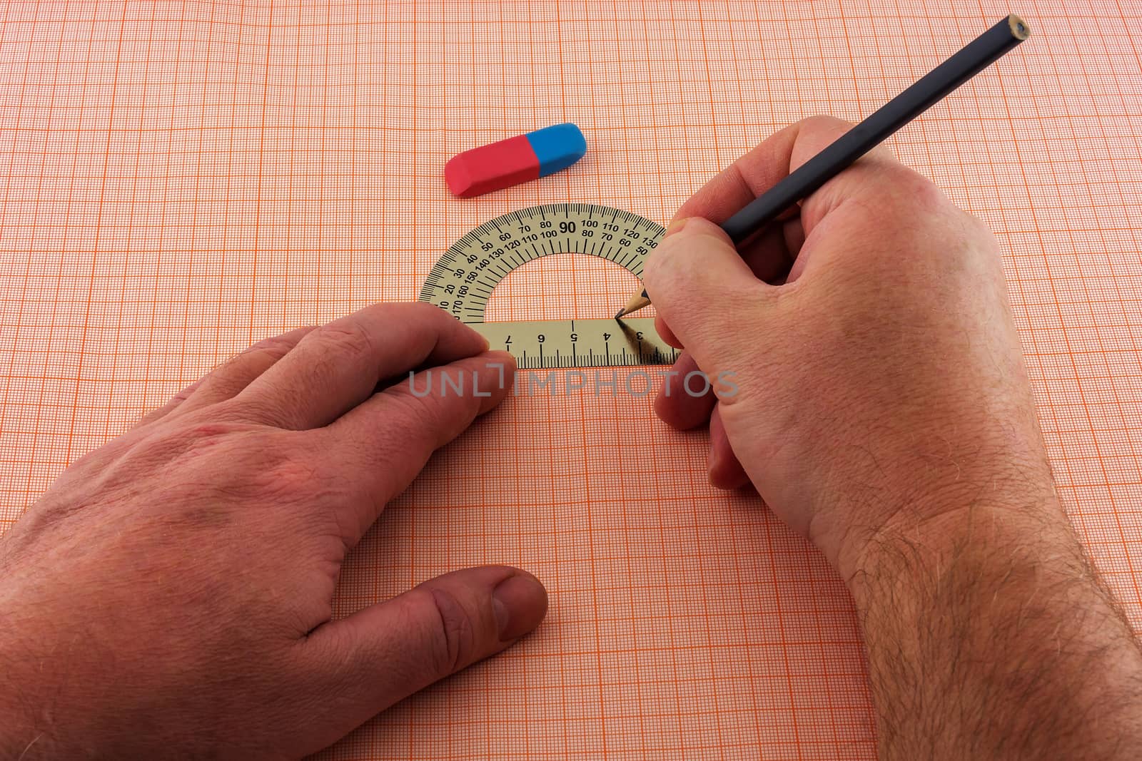 Man's hand draws a diagram on a sheet of graph paper by Grommik