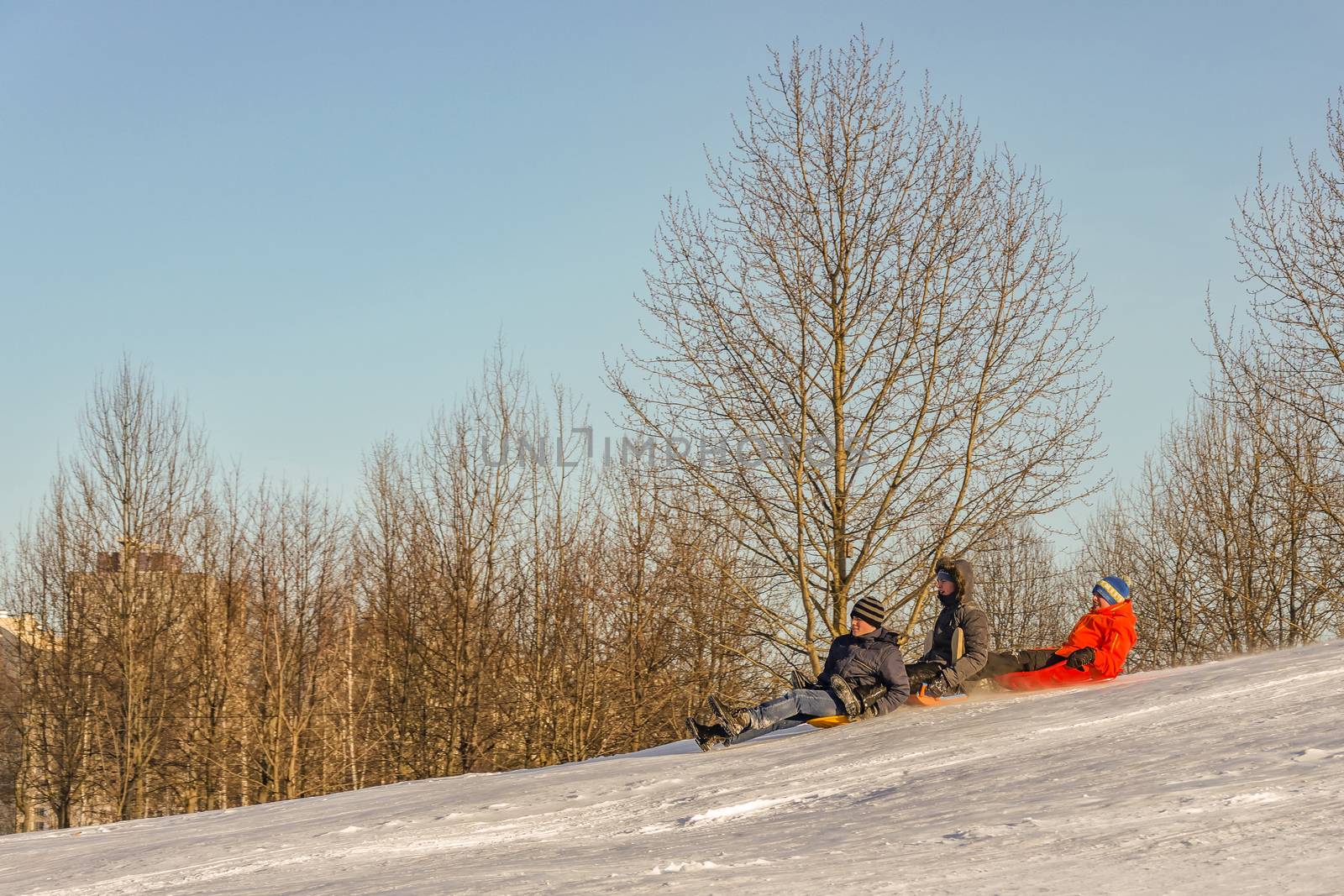 On the slope of the mountain snow three boys riding on sleds