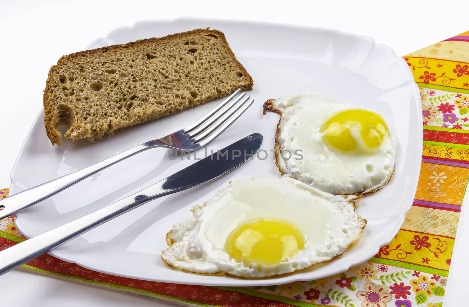 Fried eggs and black bread on a white plate by Grommik