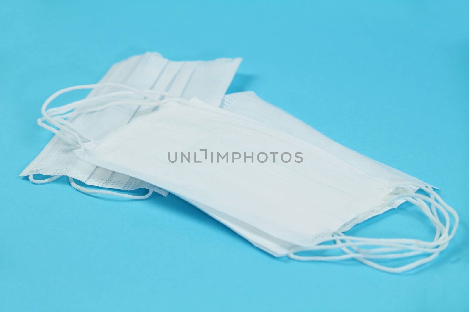 Disposable White masks on blue background by soniabonet