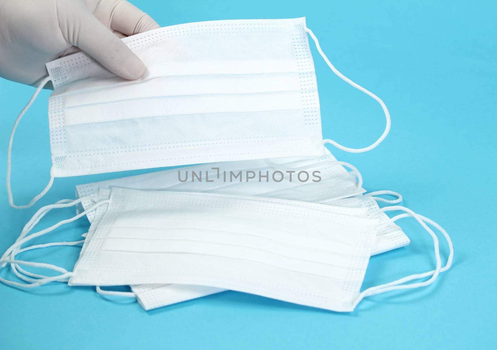 Hand with surgical gloves hanging Disposable White masks by soniabonet