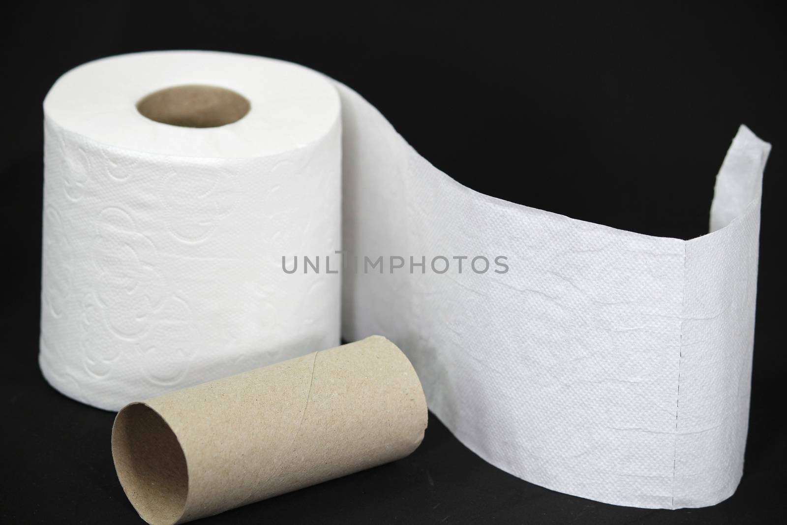 White toilet paper roll on black background next to empty one