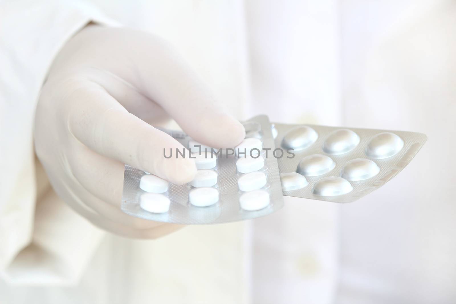 Male hand in white surgical glove holding pill blisters