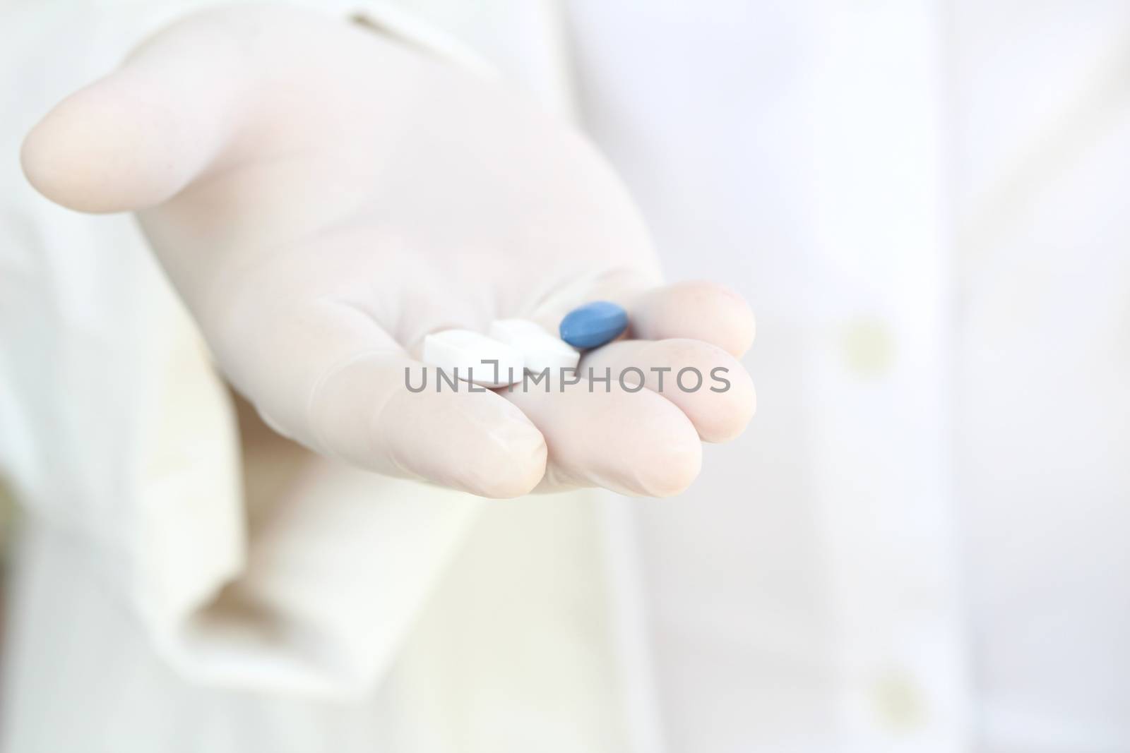 Hand in surgical glove holding pills by soniabonet