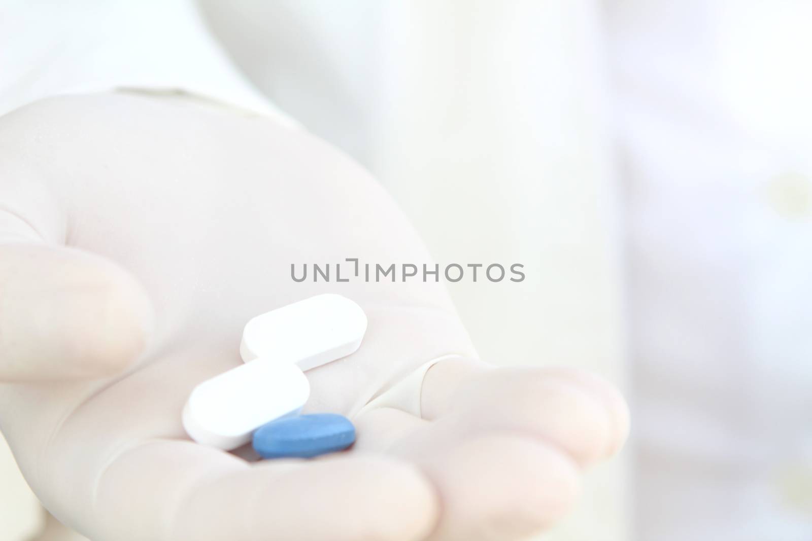 Male hand in white surgical glove holding pills