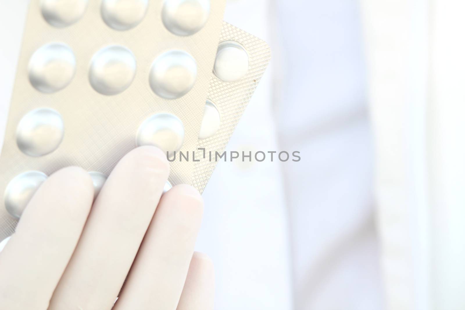 Male hand in white surgical glove holding pill blisters