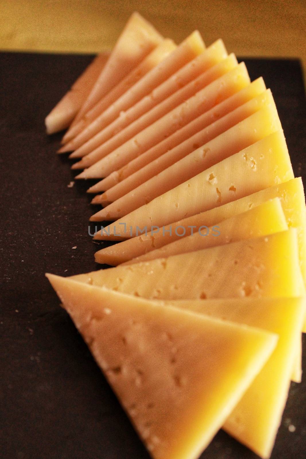 Manchego cheese slices in triangles on a black table