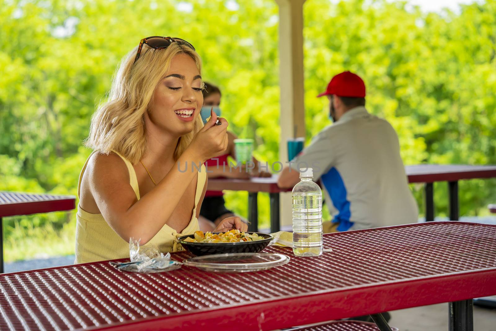A gorgeous young blonde model enjoys her lunch outdoors while maintaining a safe distance from others during the Covid-19 pandemic