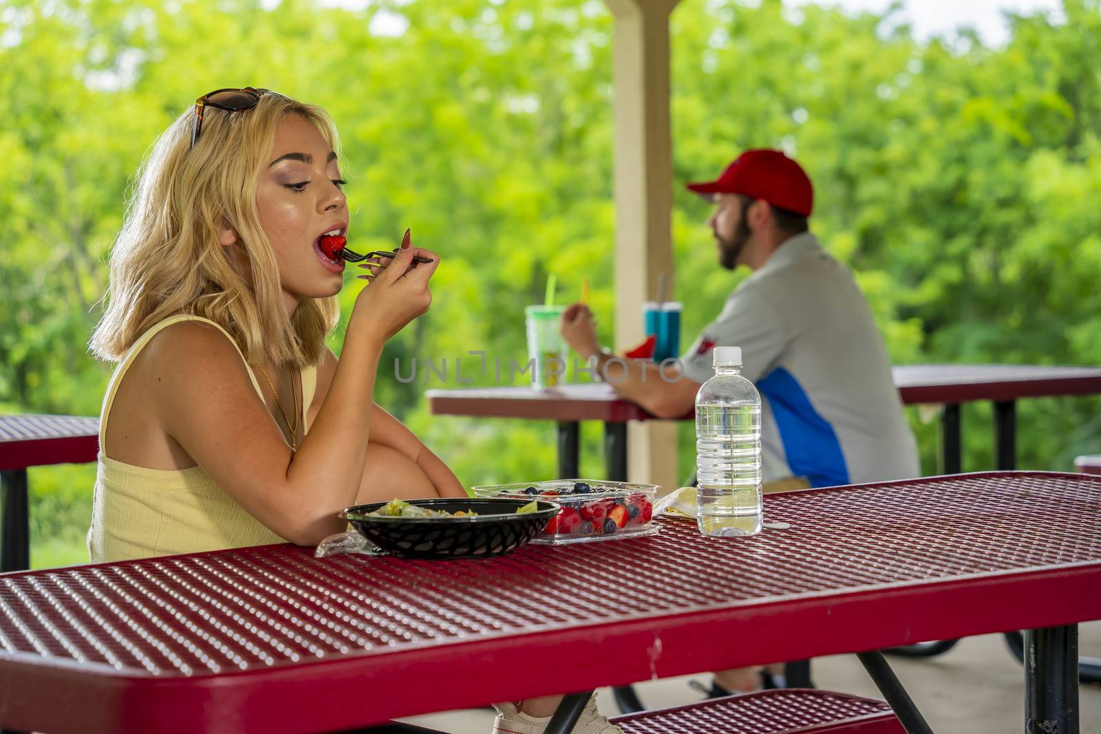 A gorgeous young blonde model enjoys her lunch outdoors while maintaining a safe distance from others during the Covid-19 pandemic