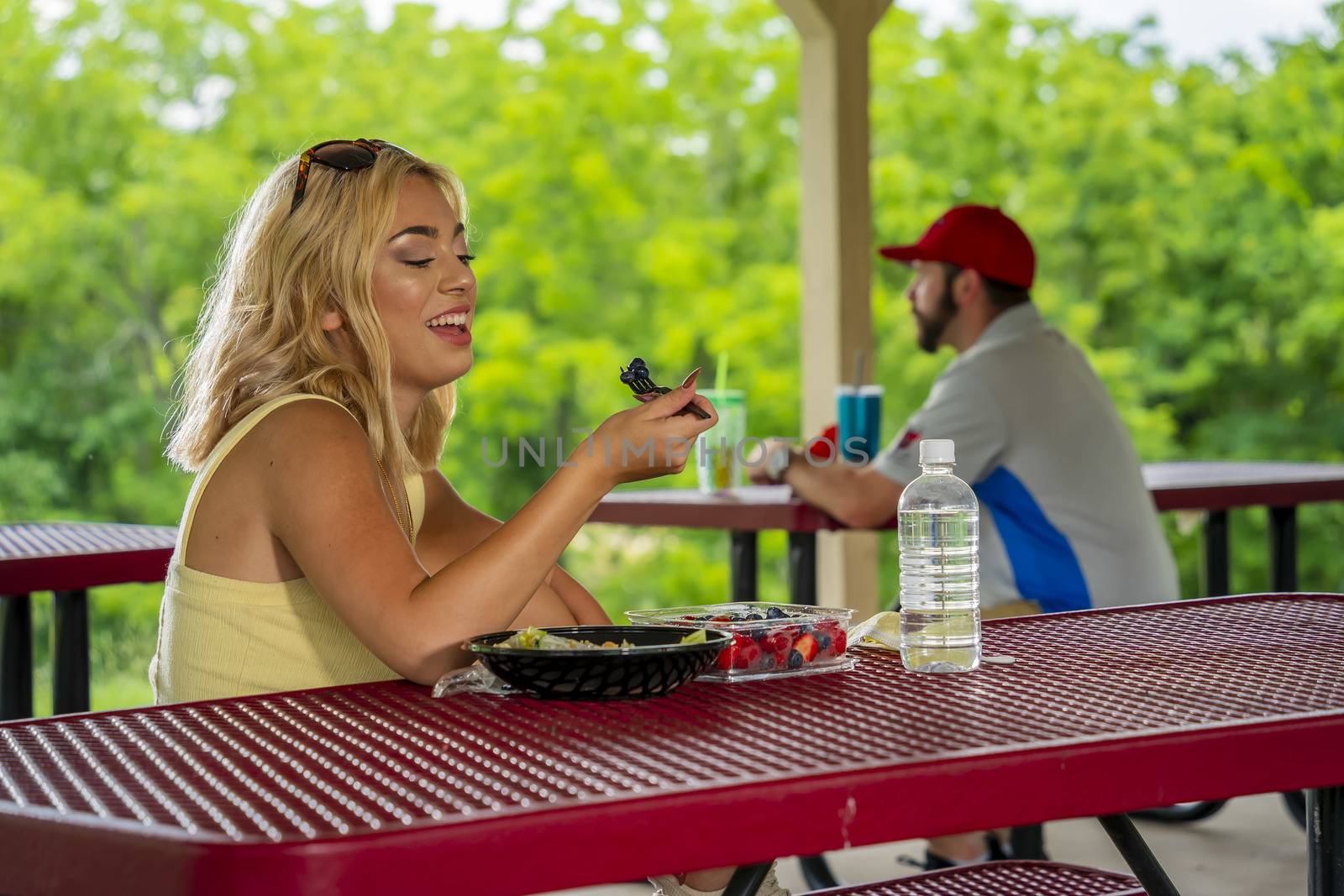 A gorgeous young blonde model enjoys her lunch outdoors while maintaining a safe distance from others during the Covid-19 pandemic